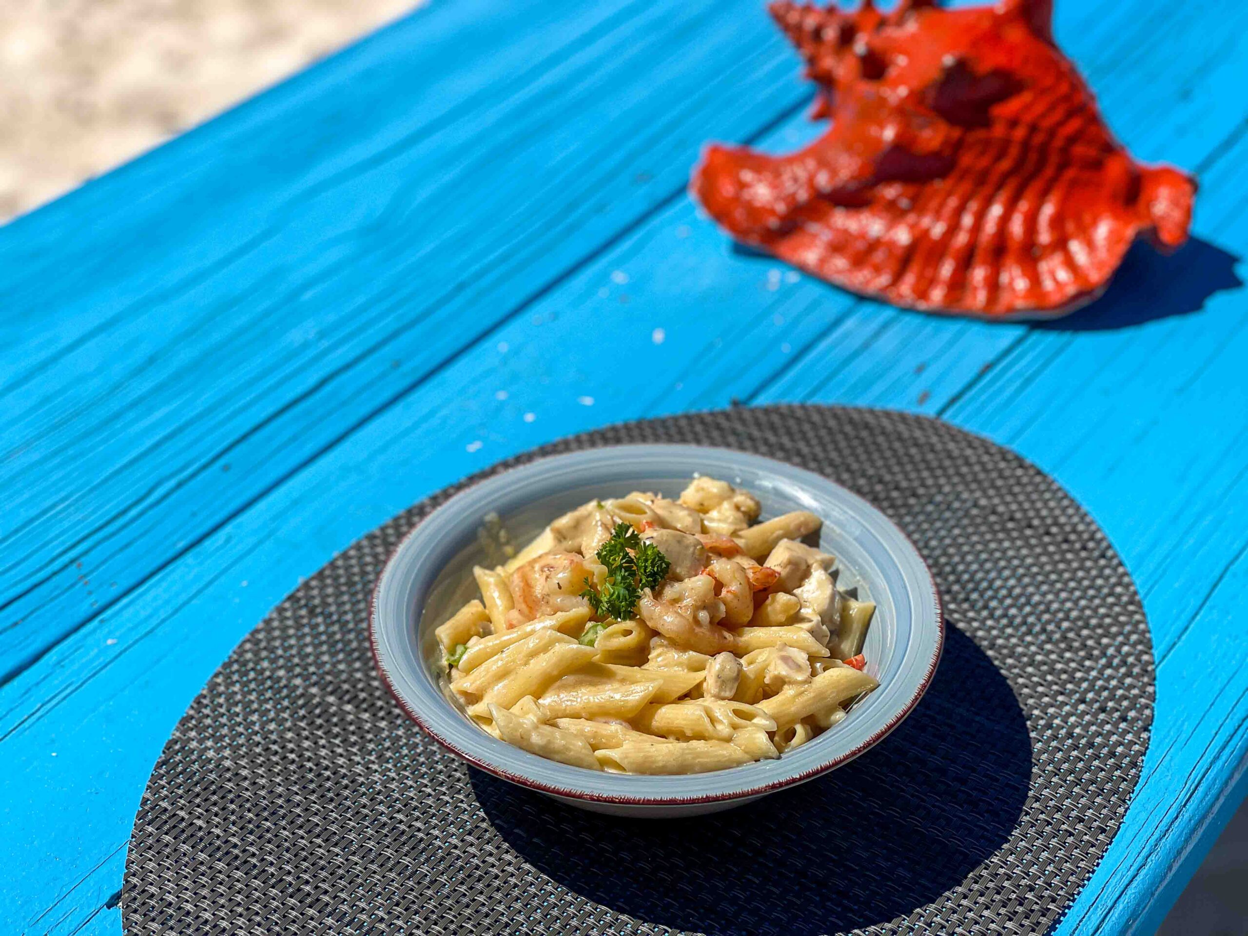 Bowl of pasta tubes on blue talbe